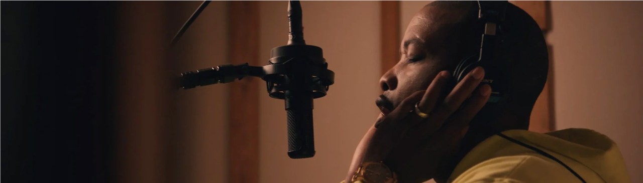 一名男性艺术家在录音室中用麦克风演唱。