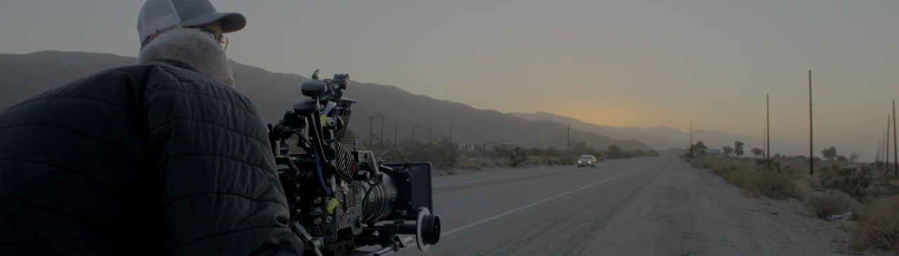 一名男性站在路边，看向面前的索尼专业摄影机，专注于拍摄周围的环境。