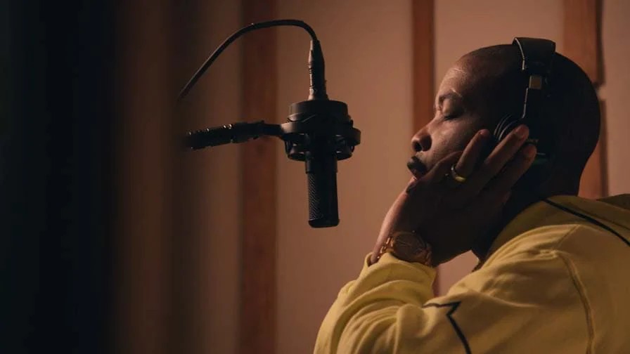 一名男性艺术家在录音室中用麦克风演唱。