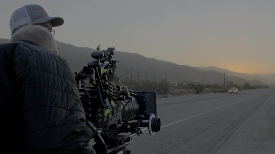 一名男性站在路边，看向面前的索尼专业摄影机，专注于拍摄周围的环境。